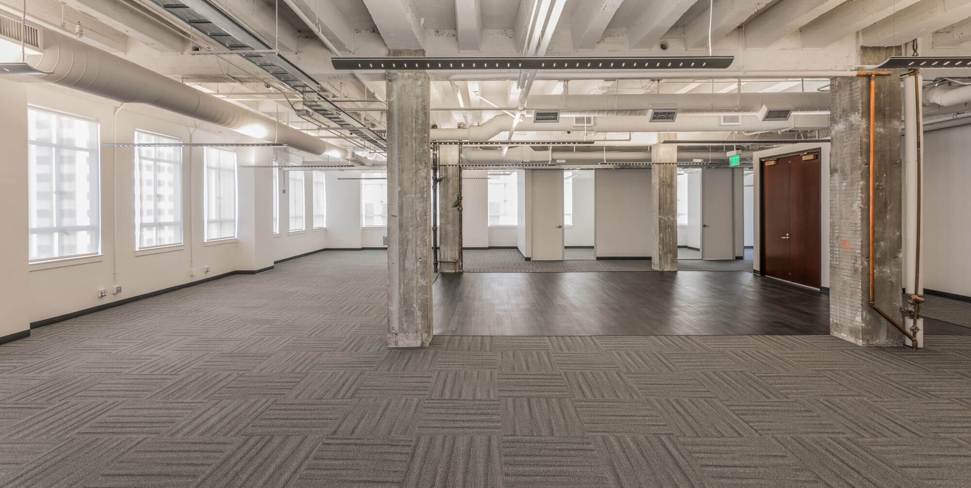 a large room with concrete pillars and wooden flooring