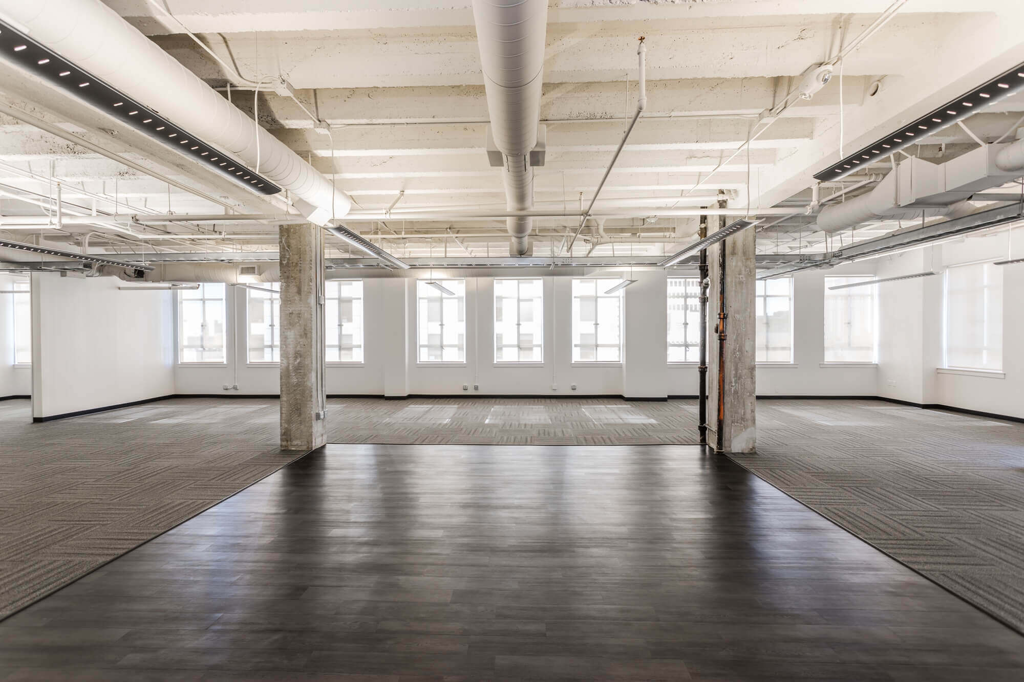 a large room with concrete pillars and wooden flooring
