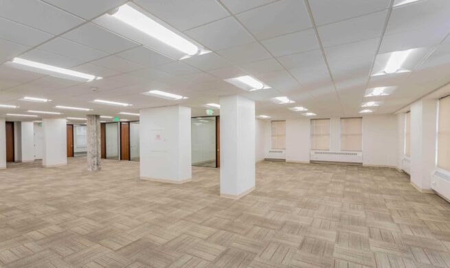 a large room with white concrete pillars and wooden flooring