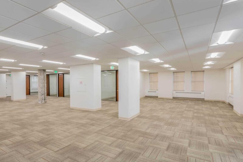 a large room with white concrete pillars and wooden flooring