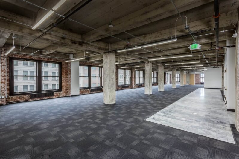 office space with black flooring and pillars