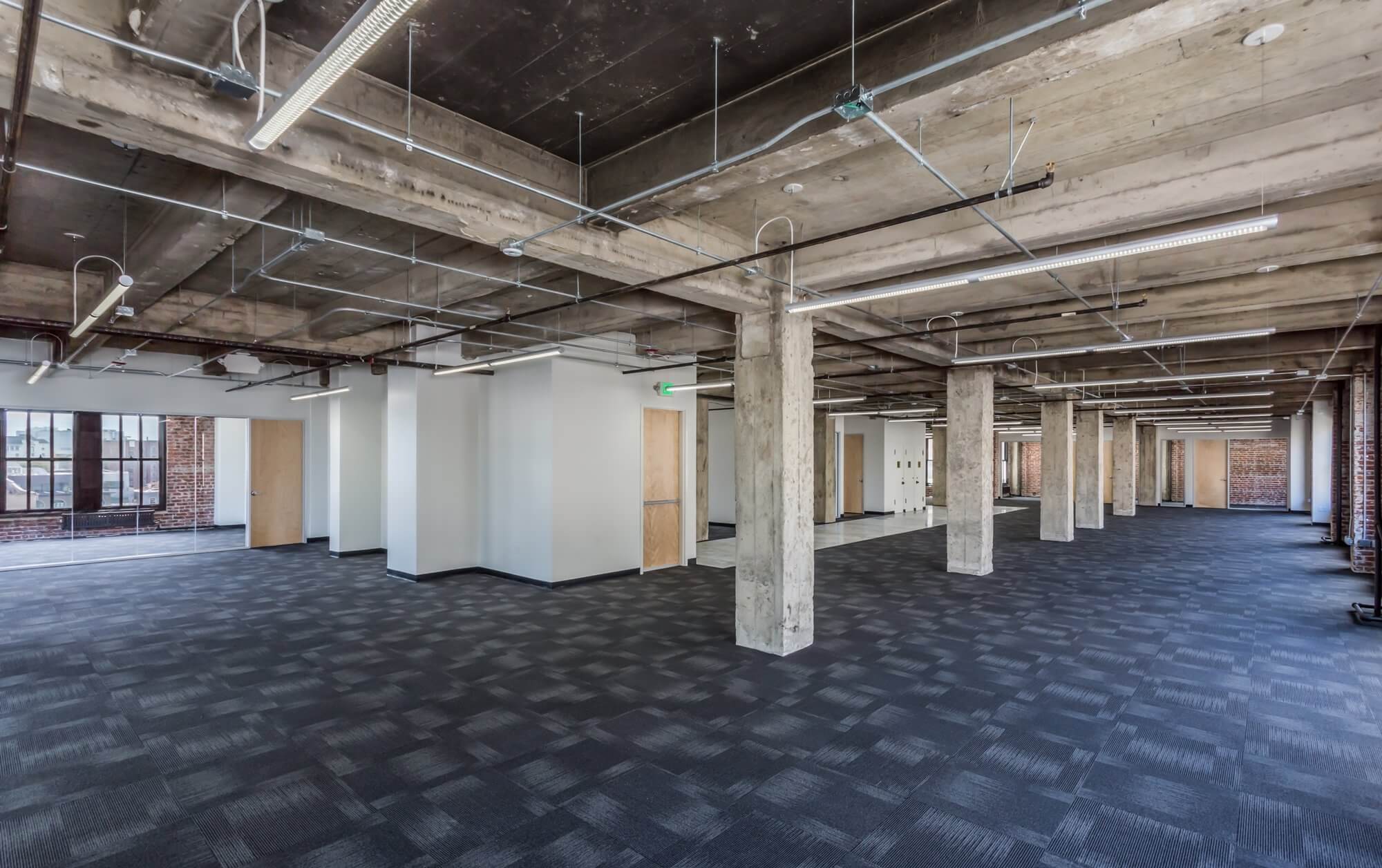 office space with black flooring, pillars, white walls and brown doors