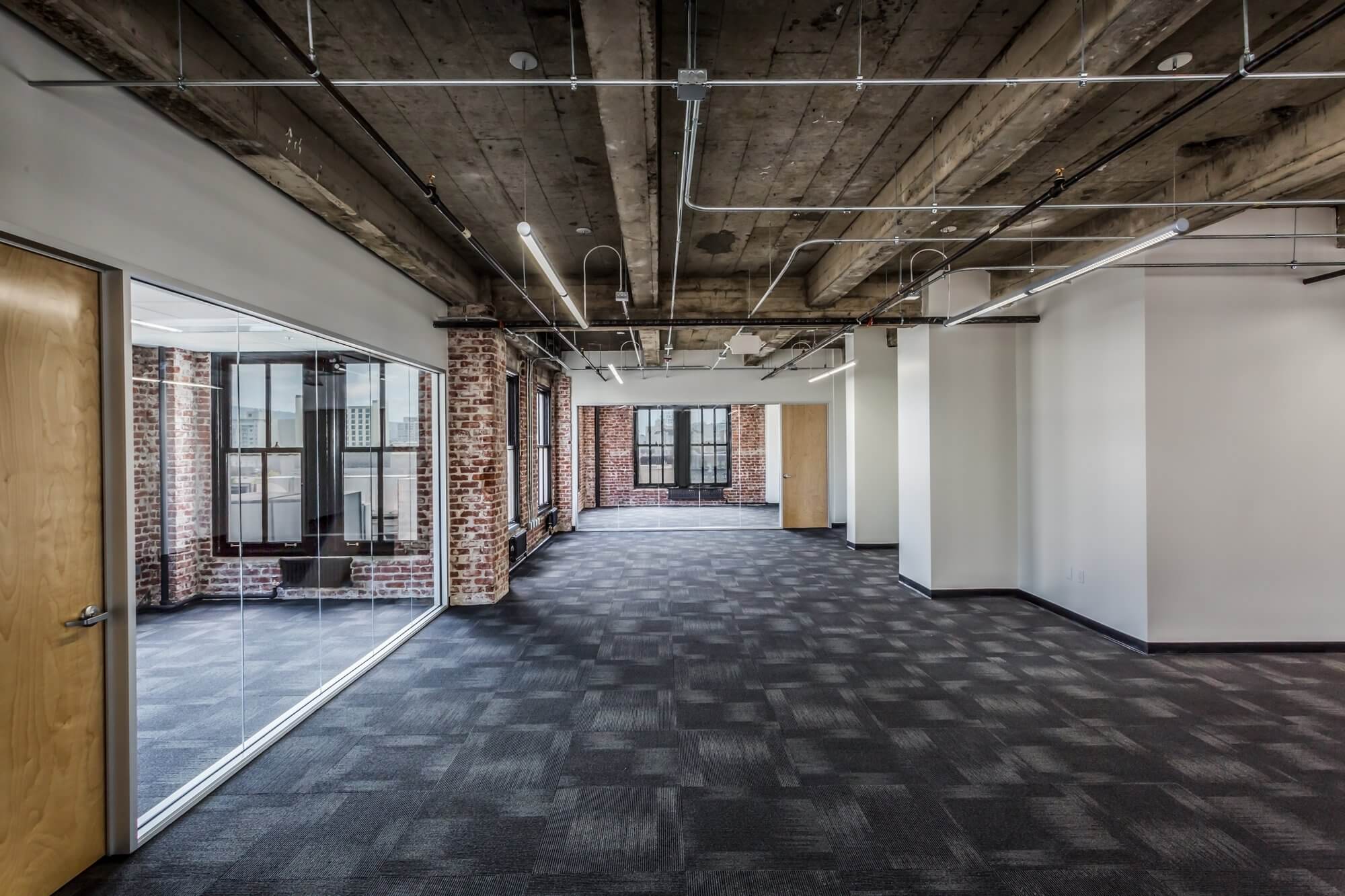 office space with black flooring, pillars, white walls and brown doors