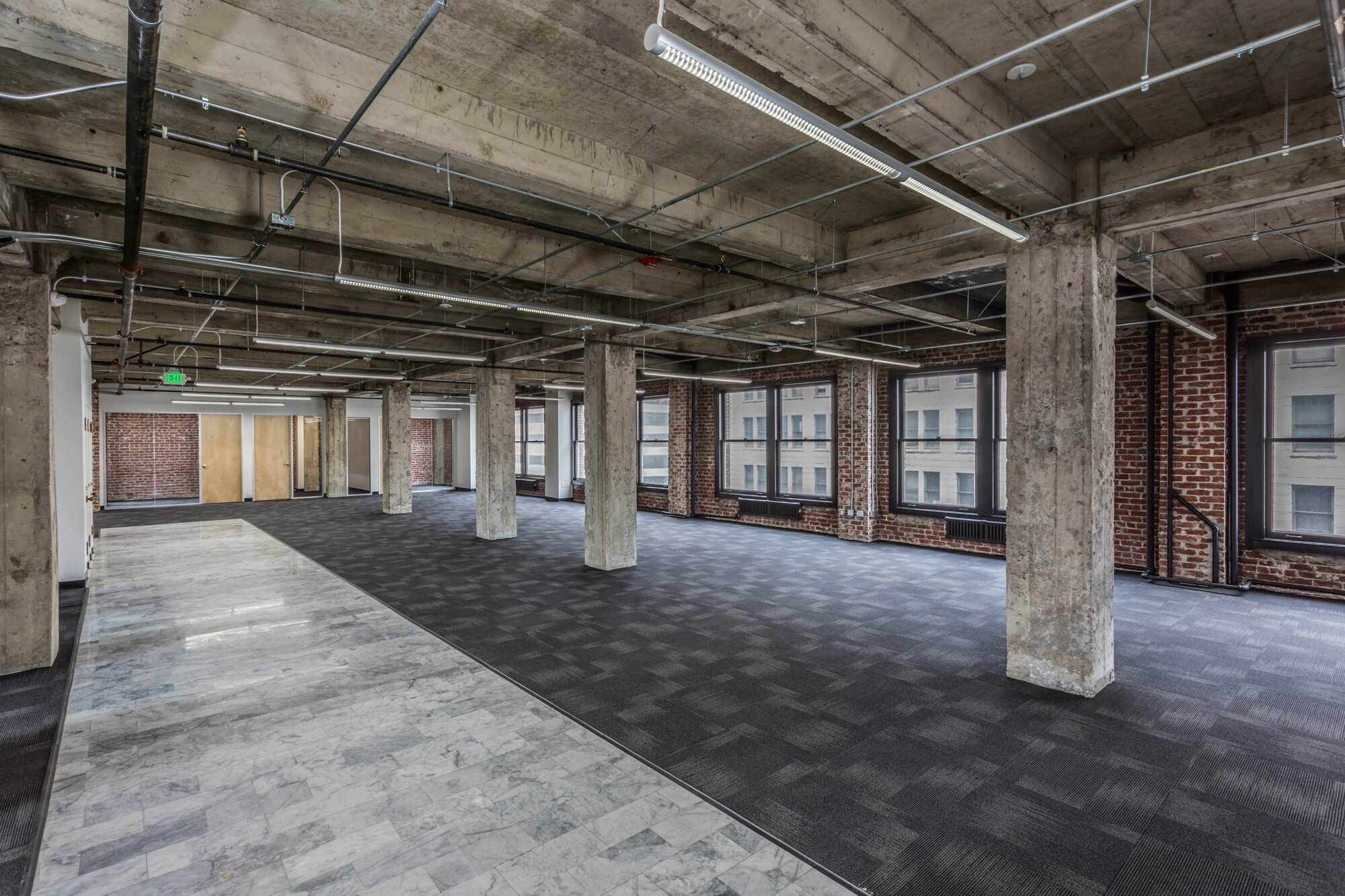 office space with black flooring, pillars, white walls and brown doors