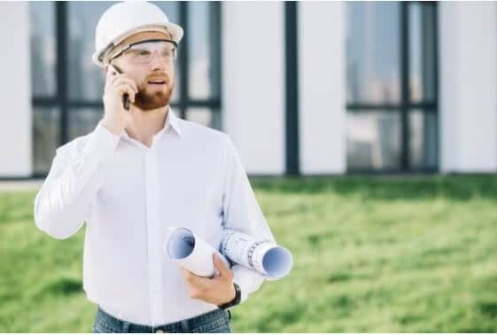 general contractor guy talking on mobile and holding a construction layout