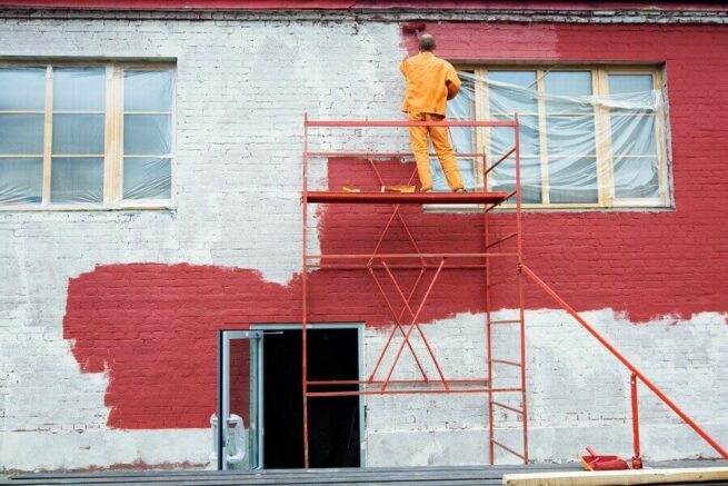 a person in a red brick building painting the wall in red color