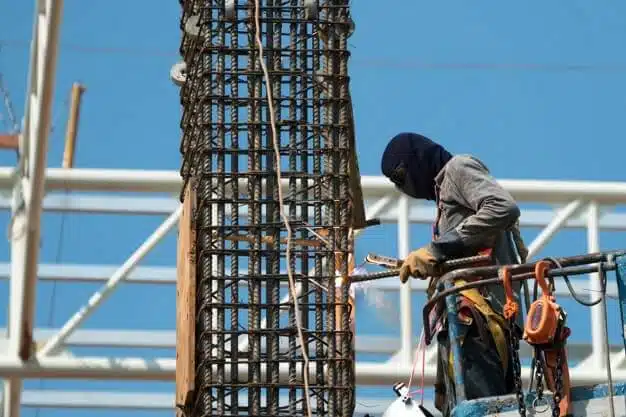 Worker using electric wheel grinding on steel structure in facto seismic retrofitting techniques