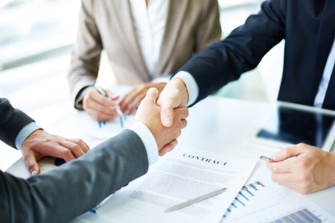 Image of a loan lender and borrower handshaking over commercial construction loan process