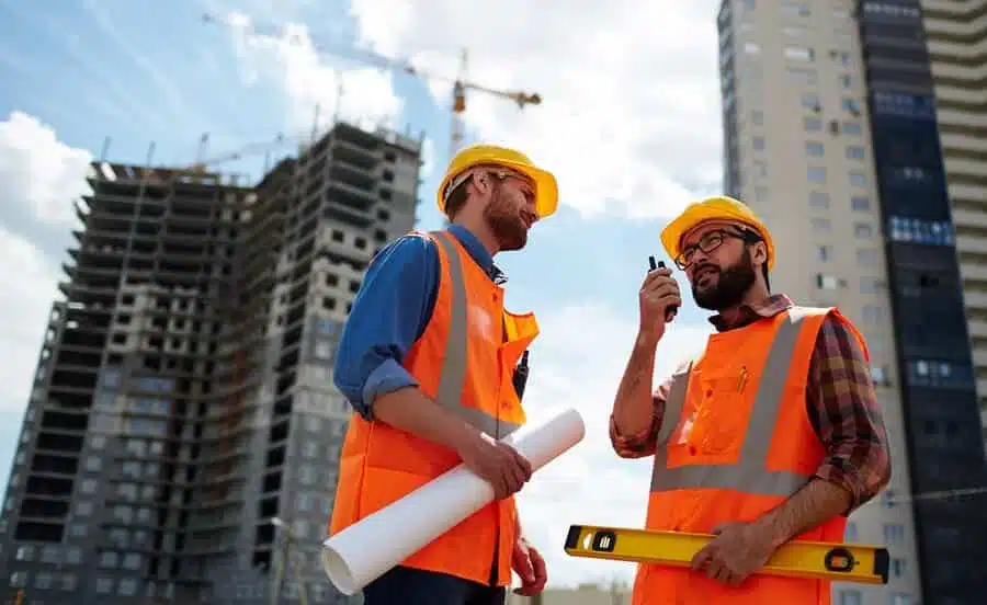 commercial contractor speaking commercial contractor speaking on walkie-talkie with co-worker near by