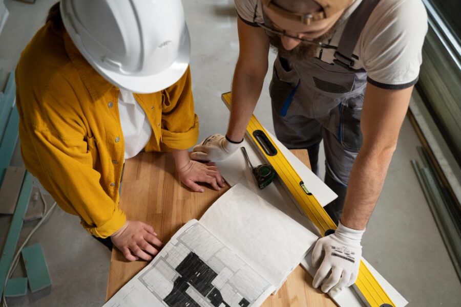 two construction workers discussing with a blueprint at the table