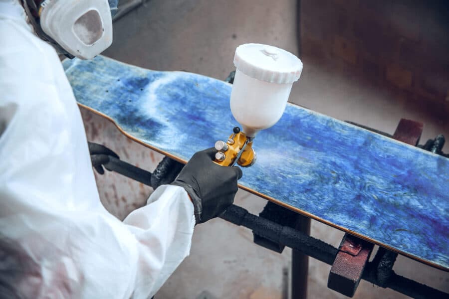 Master painter in a factory - industrial painting wood with spray gun.