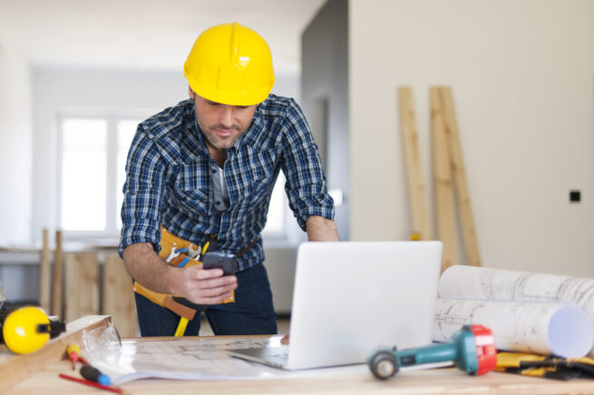 Office renovation contractor busy at work and using a mobile phone.