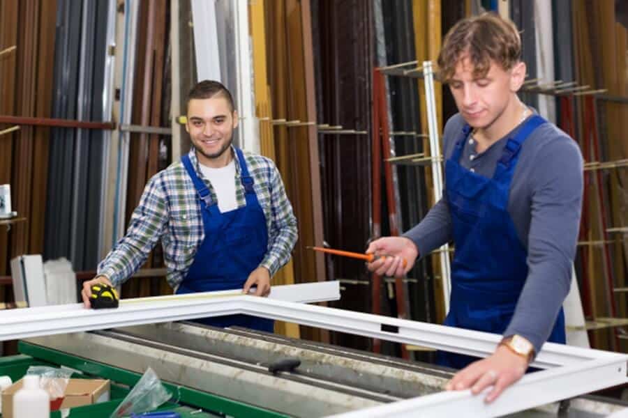 two construction workers fixing window using tools like screw driver